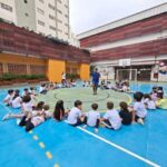Crianças sentadas em roda no pátio da escola.