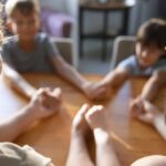 Crianças e pais de mãos dadas sobre uma mesa.